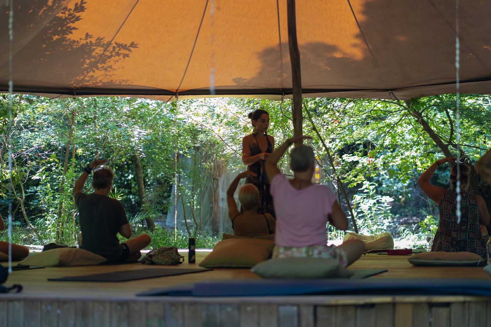 People relaxing on cushions under a shaded tent