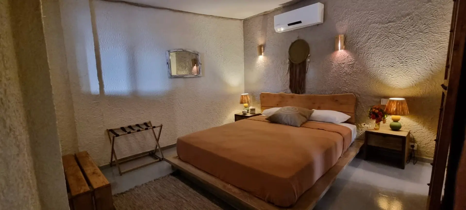 Sea front room with a wooden bed, warm lamps and textured stone walls