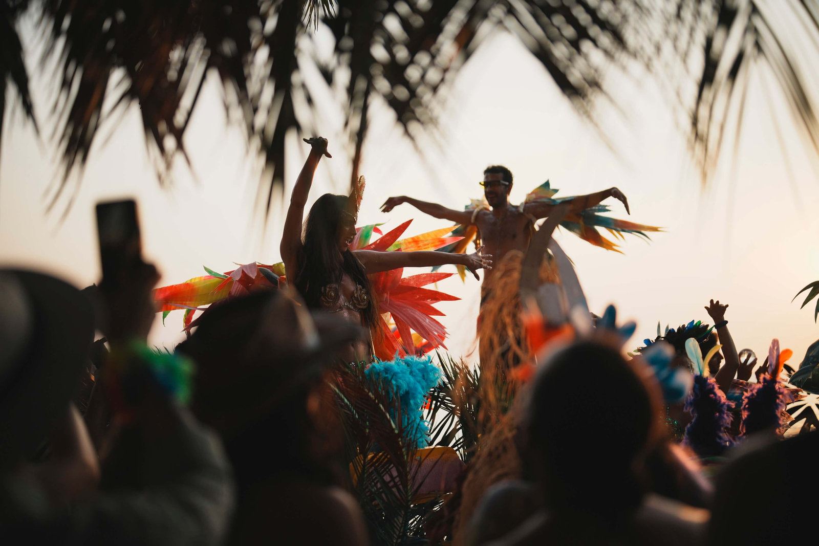 Dancers silhouetted against a sunset sky on the beach