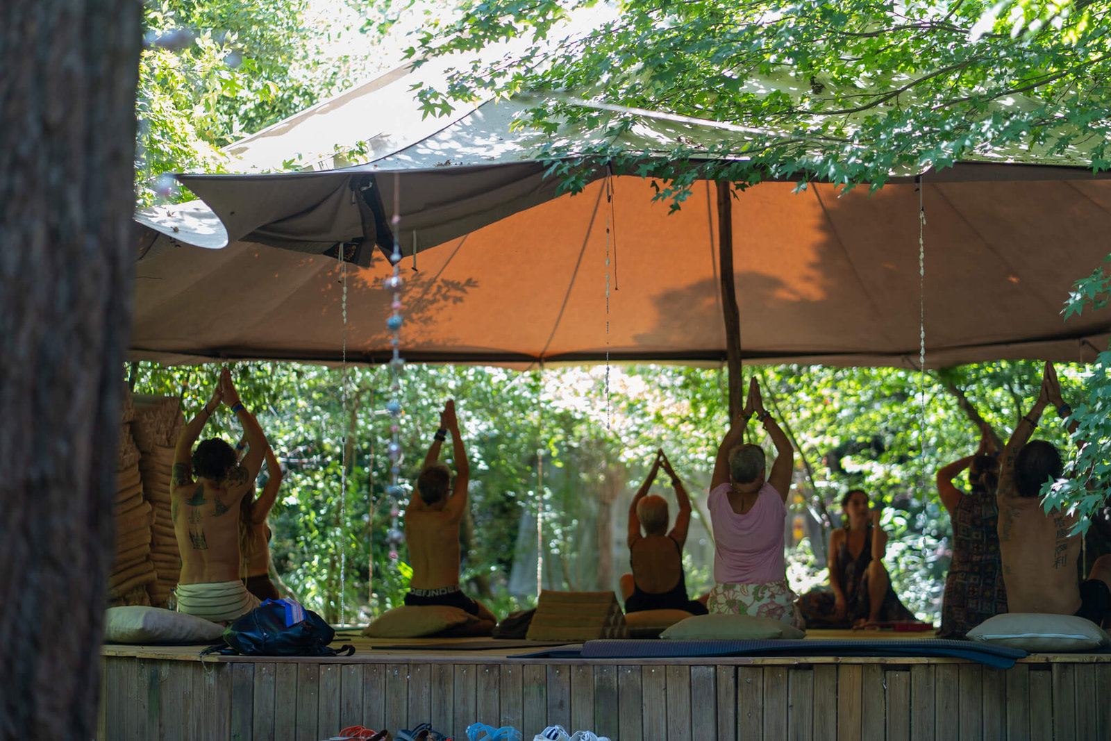 Yoga class stretching inside an open-sided tent