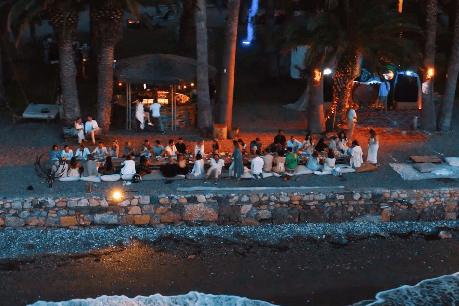 Evening gathering on the pebble beach lit by warm lights